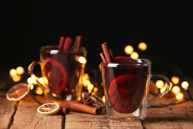 Mulled wine with cinnamon and orange on wooden table. Space for text