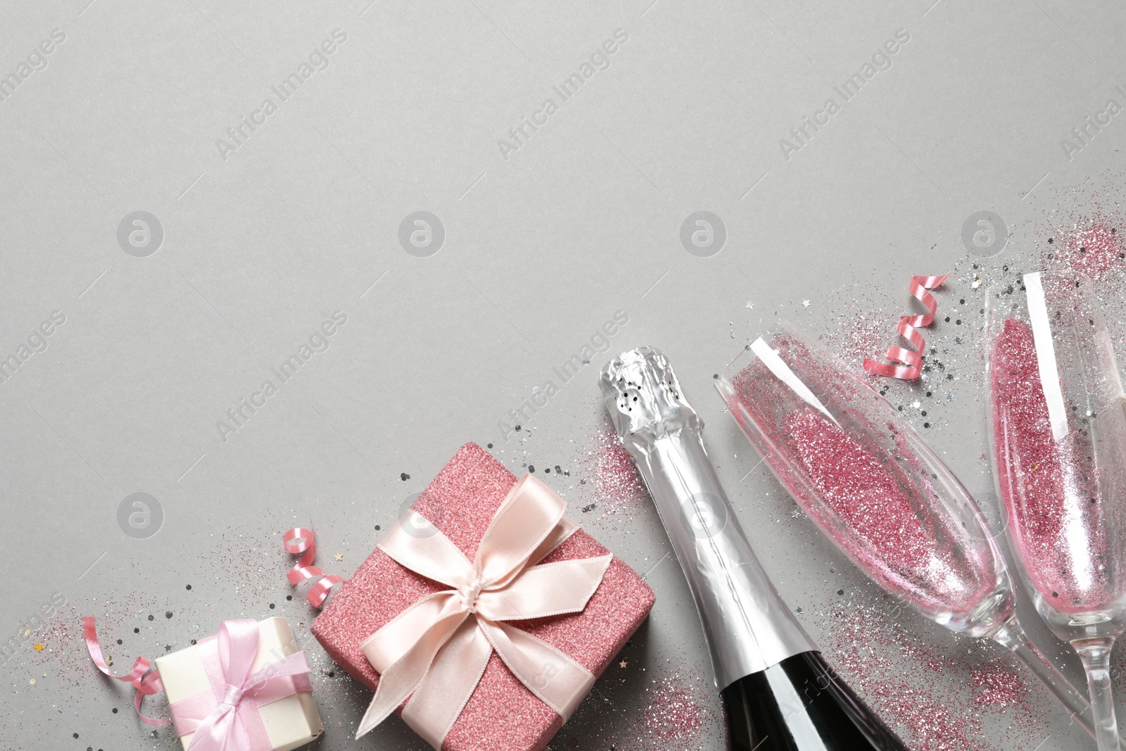 Photo of Flat lay composition with bottle of champagne for celebration on grey background. Space for text