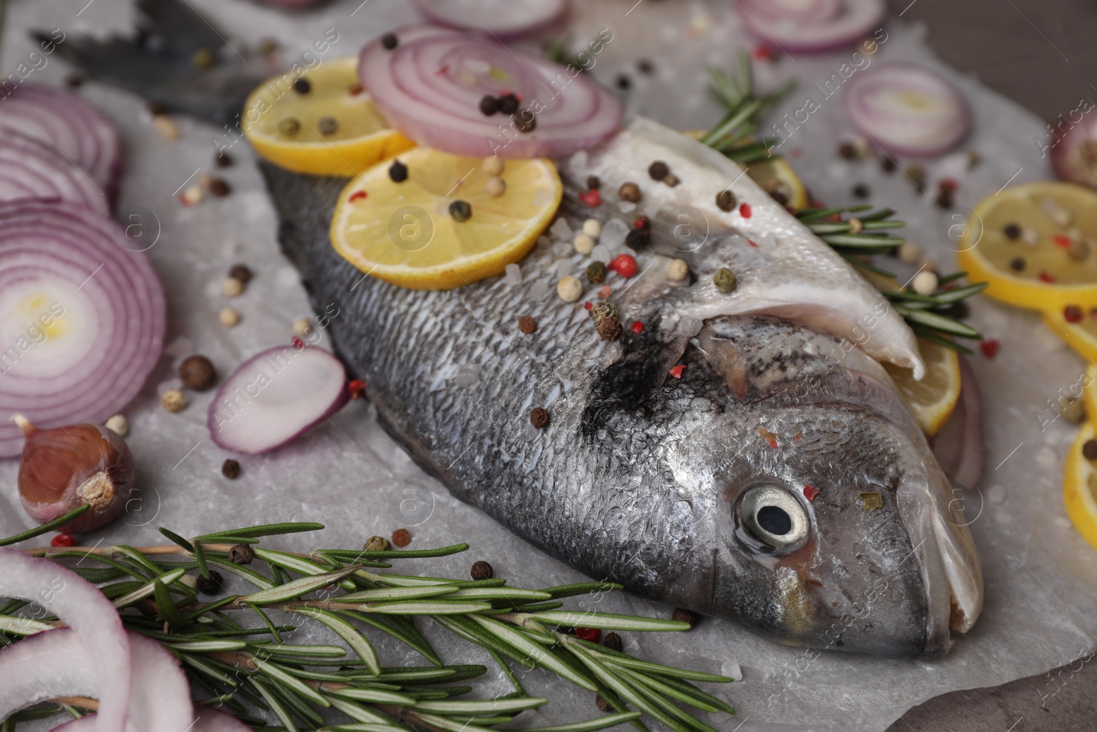 Photo of Fresh raw dorado fish with spices, lemon and onion on table, closeup