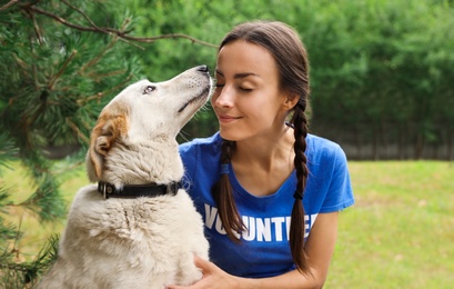 Female volunteer with homeless dog at animal shelter outdoors