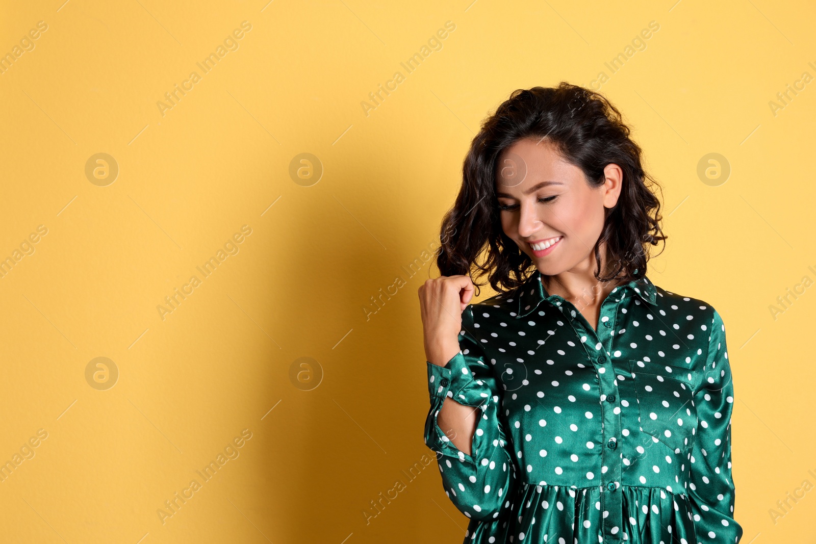 Photo of Happy young woman in bright dress on yellow background. Space for text