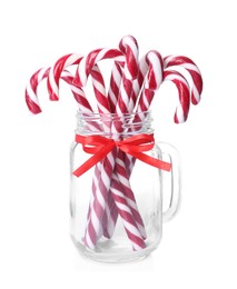 Photo of Sweet Christmas candy canes in glass mason jar on white background