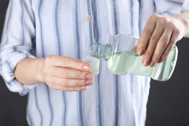 Woman pouring mouthwash from bottle into lid, closeup