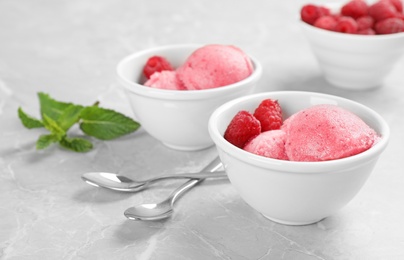 Photo of Bowls with delicious raspberry ice cream on grey marble table