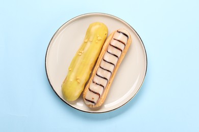 Delicious eclairs covered with glaze on light blue background, top view