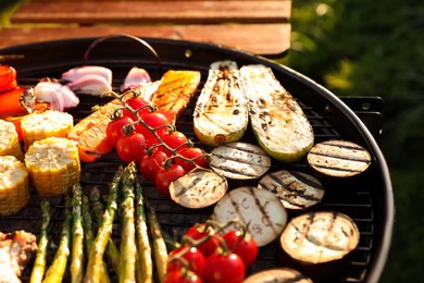 Photo of Delicious grilled vegetables and meat on barbecue grill outdoors, closeup