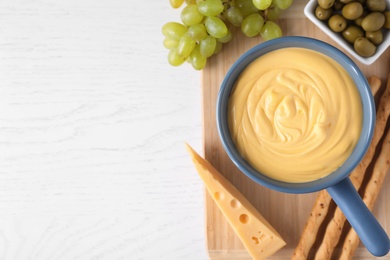 Photo of Flat lay composition with pot of cheese fondue and products on white wooden table, space for text