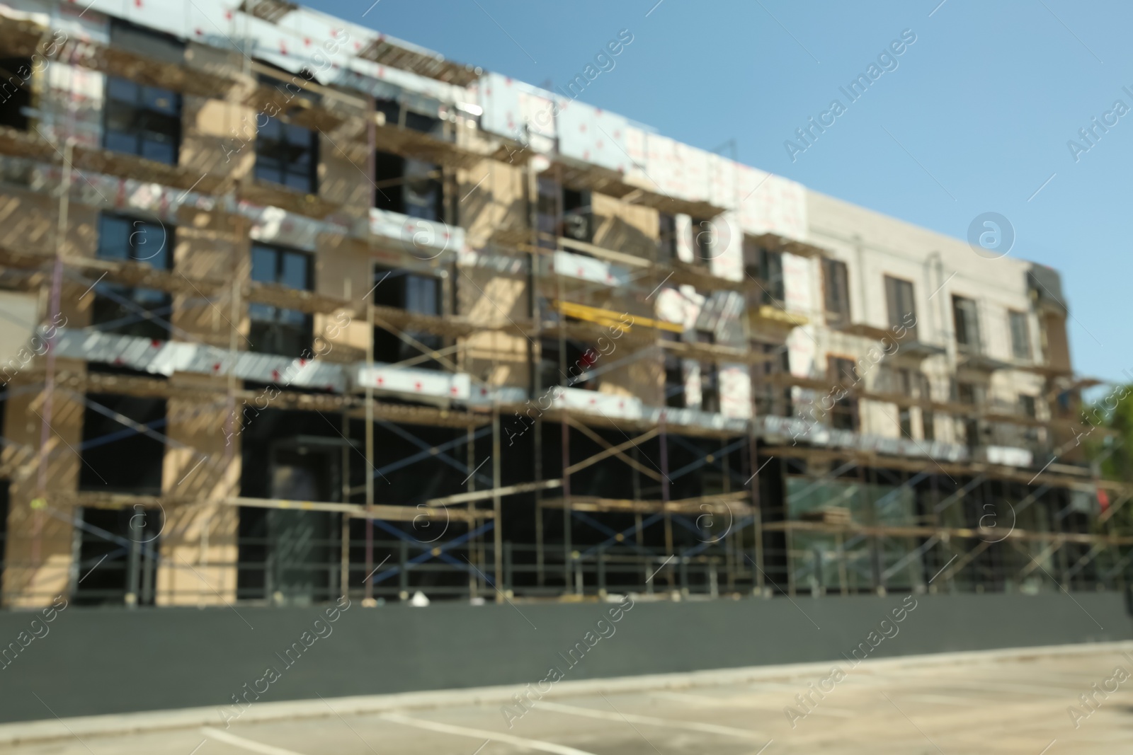 Photo of Blurred view of unfinished building with scaffolding against blue sky