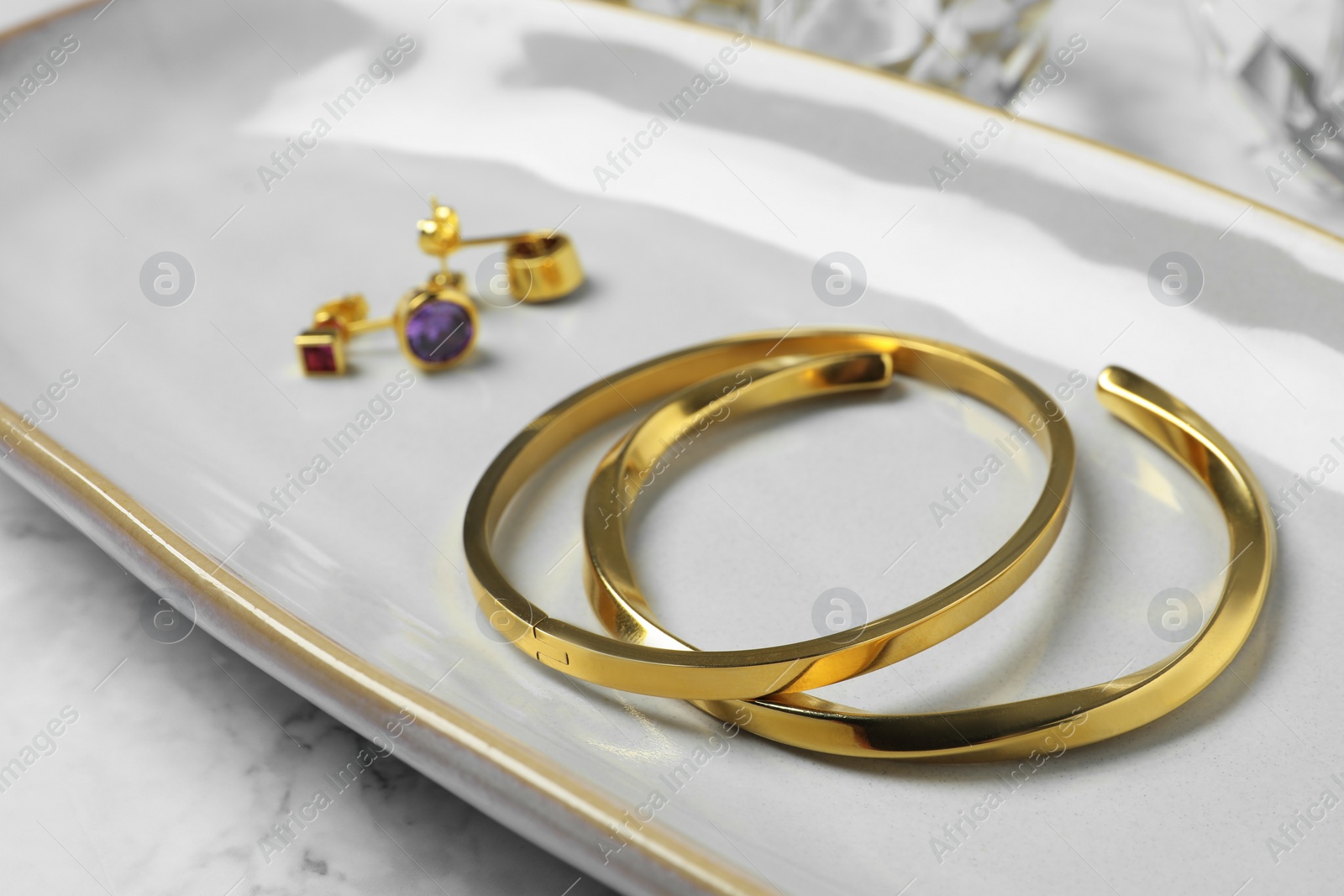 Photo of Elegant bracelets and earrings on white table, closeup