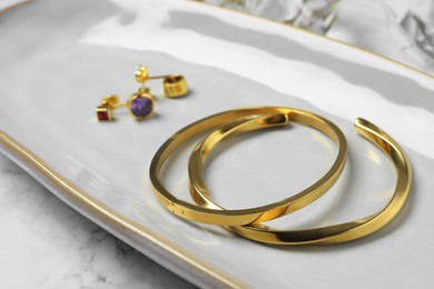 Photo of Elegant bracelets and earrings on white table, closeup