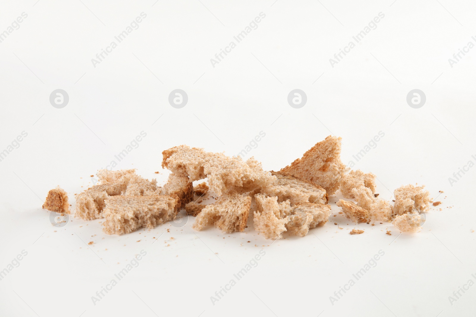 Photo of Scattered bread crumbs on white background, closeup