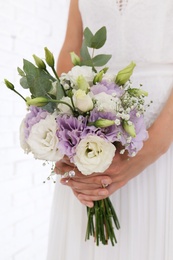 Bride holding beautiful bouquet with Eustoma flowers indoors, closeup