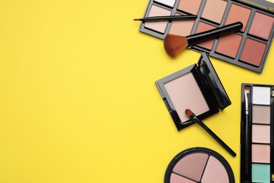 Different contouring palettes and brushes on yellow background, flat lay with space for text. Professional cosmetic product