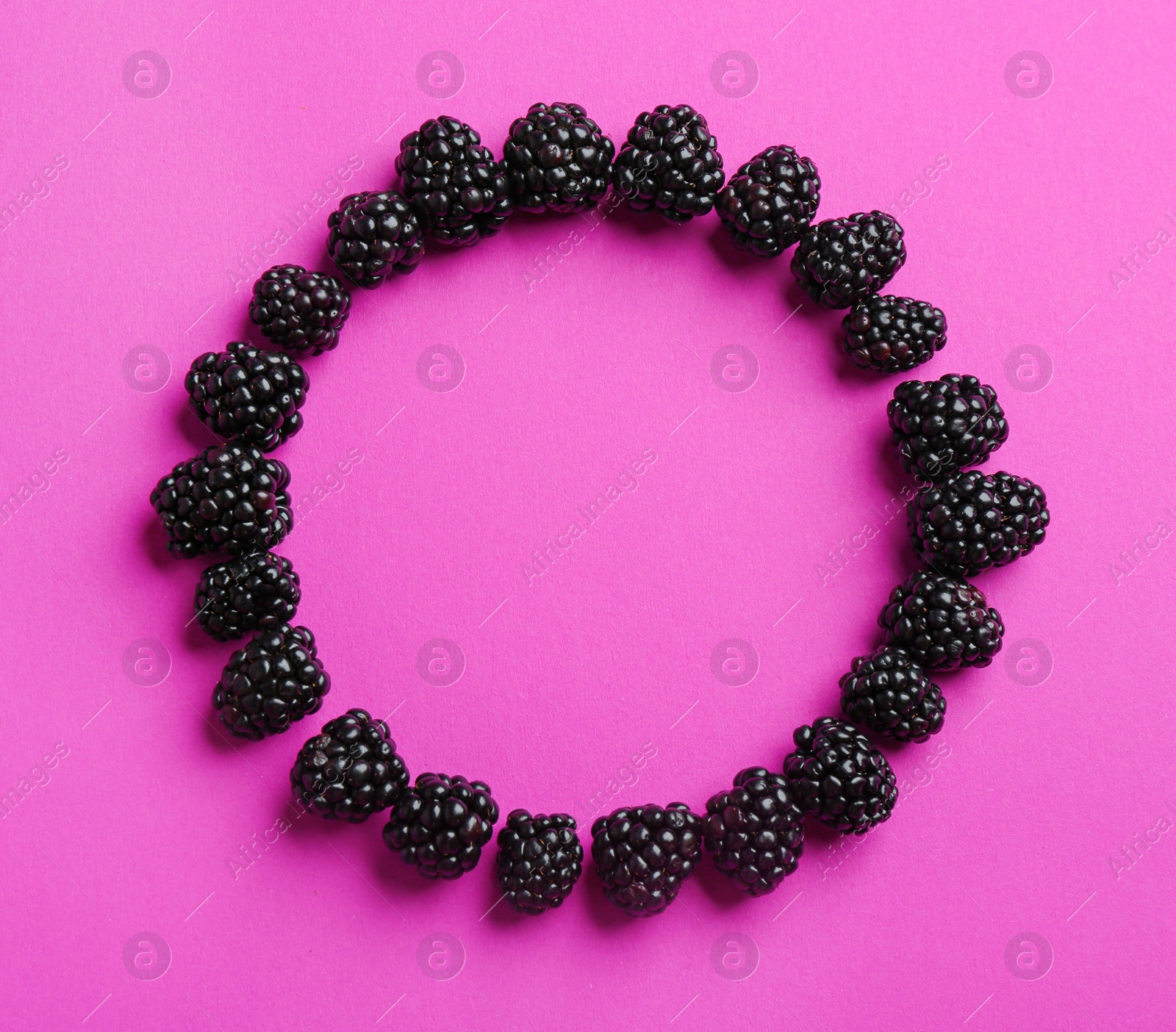 Photo of Frame made with ripe blackberries on purple background, top view. Space for text