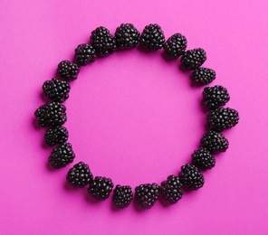 Frame made with ripe blackberries on purple background, top view. Space for text