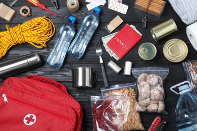 Photo of Disaster supply kit for earthquake on black wooden table, flat lay