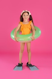 Photo of Cute little child in beachwear with bright inflatable ring on pink background