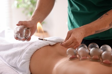 Photo of Therapist giving fire cupping treatment to patient indoors, closeup