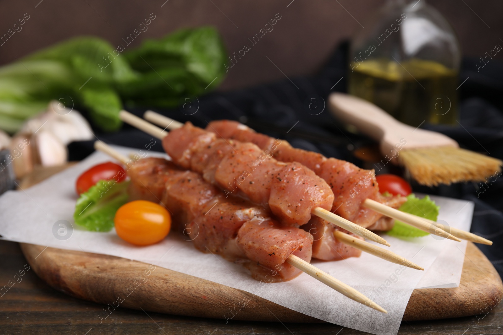 Photo of Skewers with cut raw marinated meat on wooden table, closeup