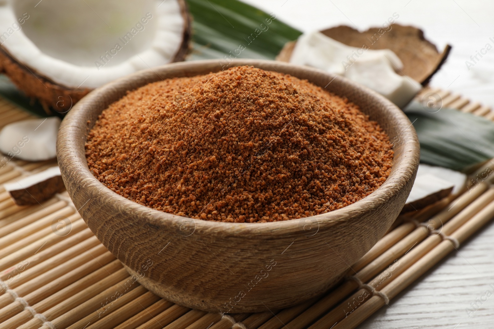 Photo of Natural coconut sugar in bowl on white wooden table