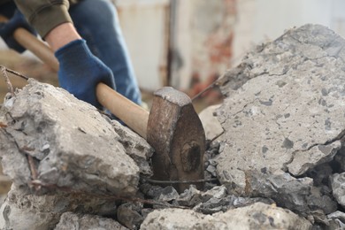 Photo of Man breaking stones with sledgehammer outdoors, closeup