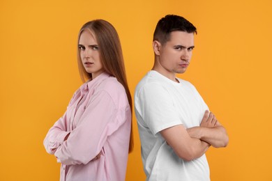 Portrait of resentful couple with crossed arms on orange background