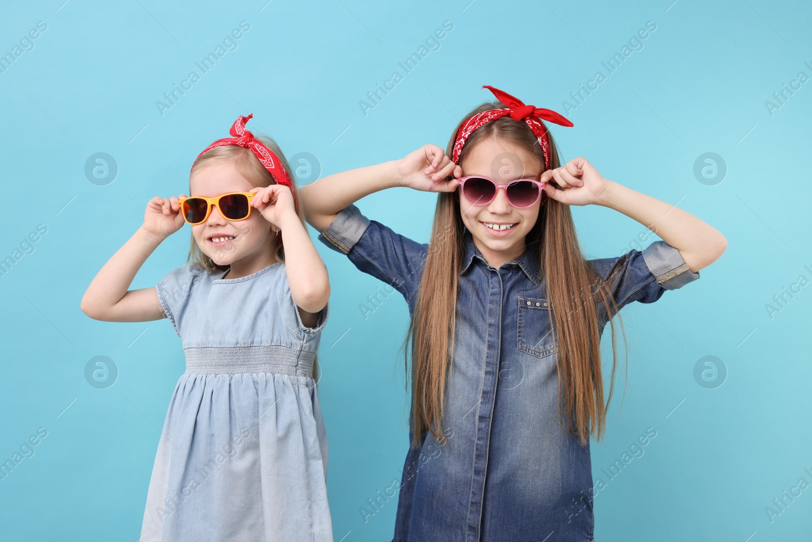 Photo of Cute little sisters on light blue background