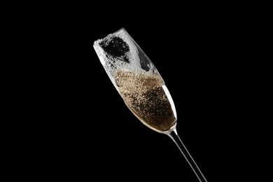 Photo of Glass of fizzy champagne on black background, closeup