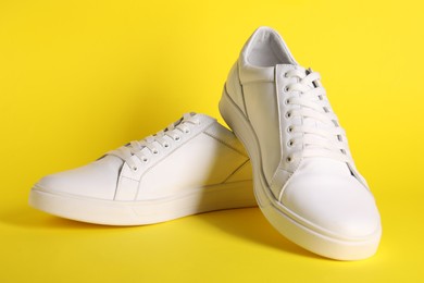 Photo of Pair of stylish white sneakers on yellow background