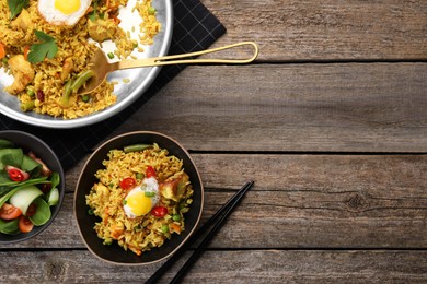Photo of Tasty rice with meat, egg and vegetables in bowl served on wooden table, flat lay. Space for text