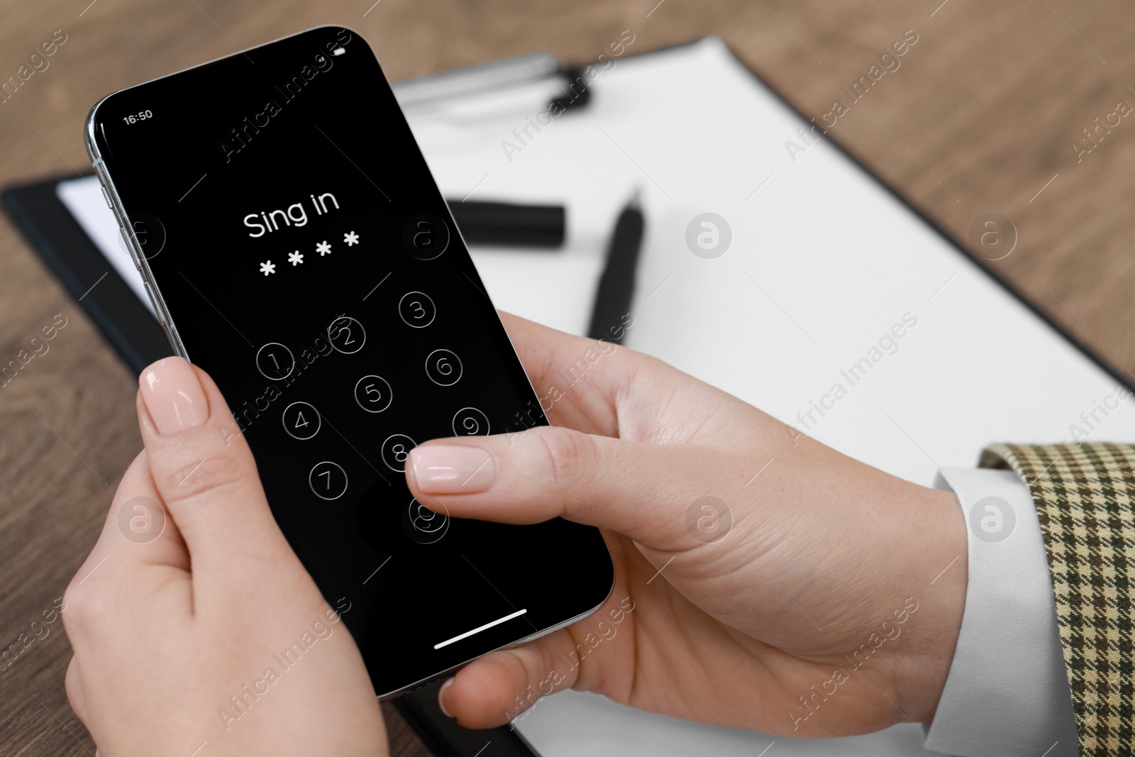 Photo of Woman unlocking smartphone with blocked screen at wooden table, closeup