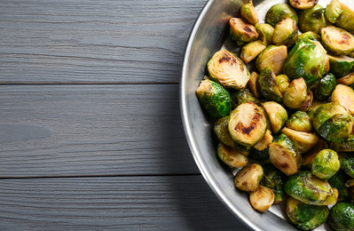 Photo of Delicious roasted brussels sprouts on grey wooden table, top view. Space for text