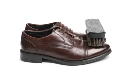 Stylish men's shoes and cleaning brush on white background