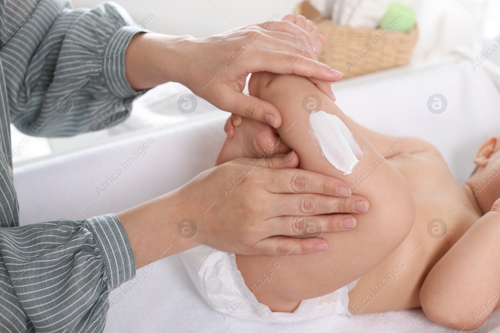 Photo of Mother applying body cream on her little baby at home, closeup