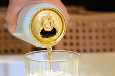 Photo of Man pouring beer from can into glass at table, closeup. Space for text