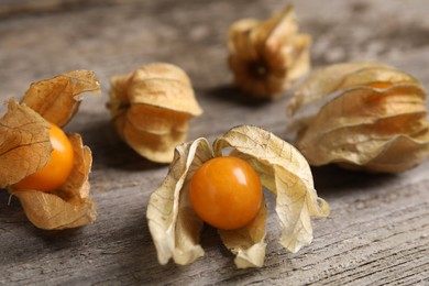 Photo of Ripe physalis fruits with dry husk on wooden table, closeup