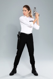 Female security guard in uniform with gun on grey background