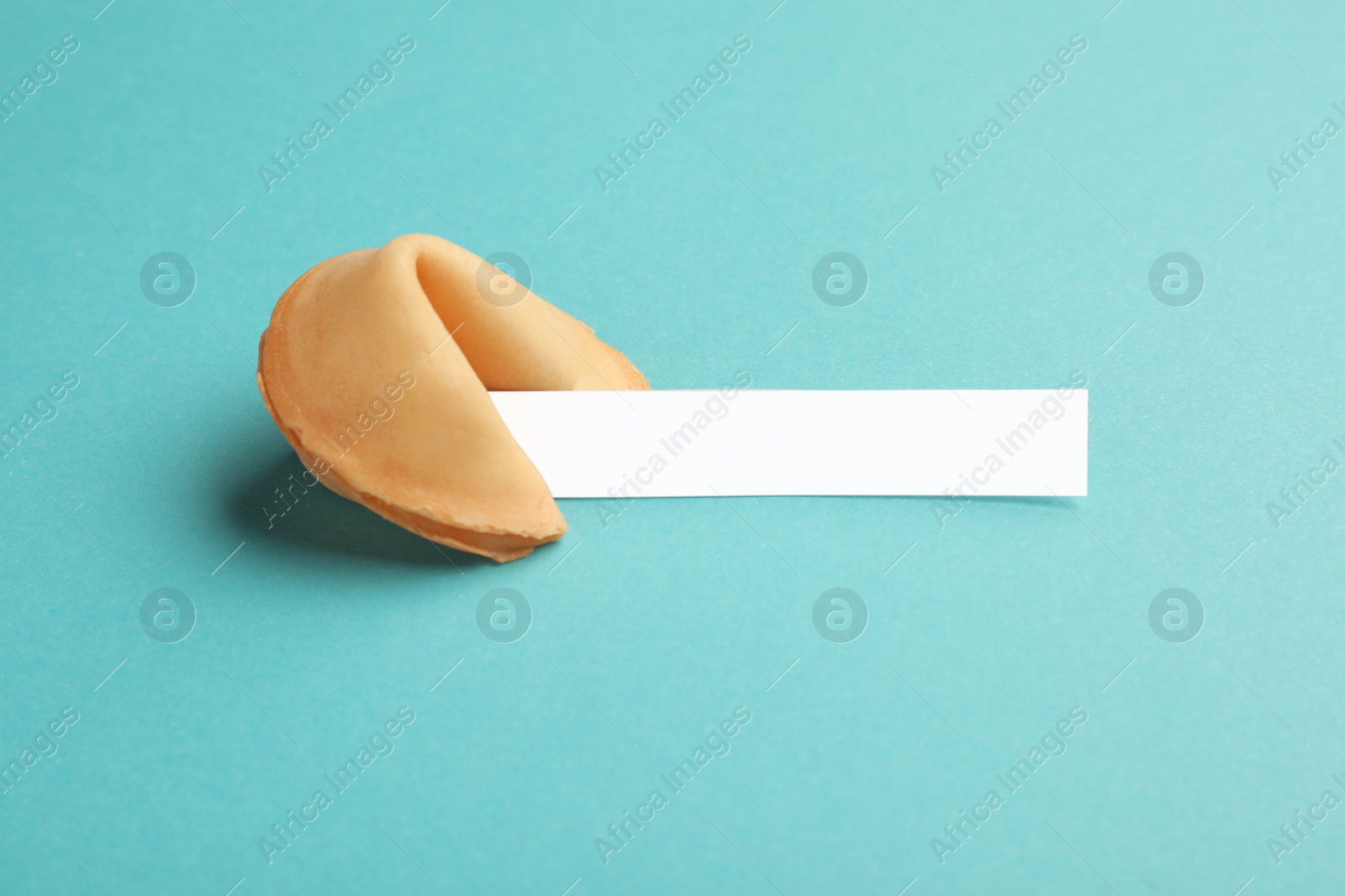 Photo of Tasty fortune cookie with predictions on light blue background. Space for text