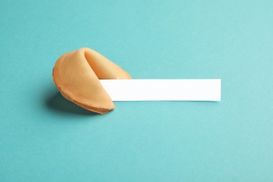 Photo of Tasty fortune cookie with predictions on light blue background. Space for text