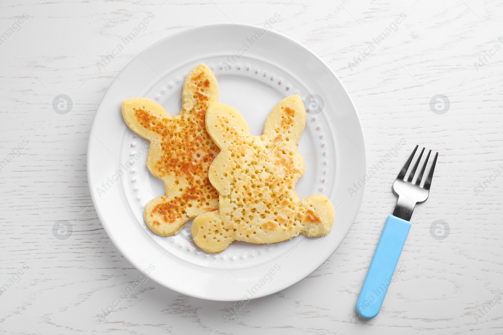 Photo of Tasty bunny shaped pancakes served on white wooden table, flat lay. Creative idea for kids breakfast