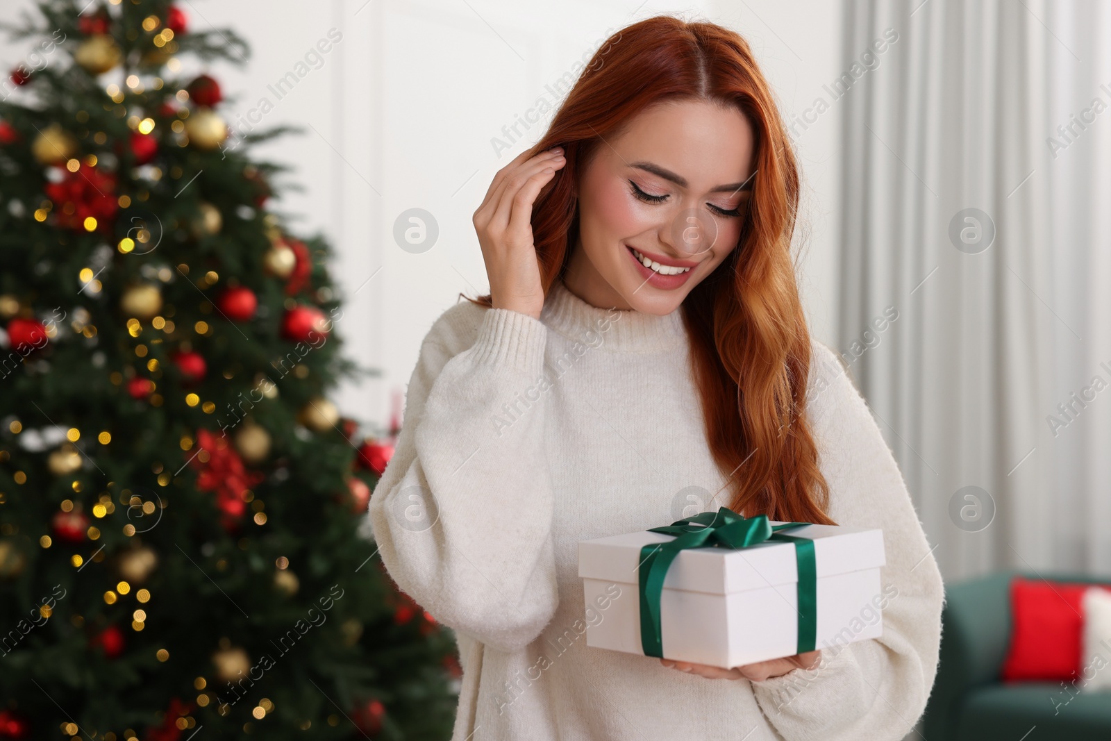 Photo of Beautiful young woman with Christmas gift at home