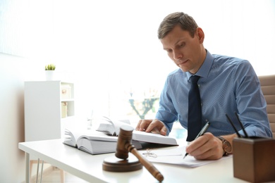 Photo of Notary working with papers and judge gavel on table in office. Law and justice concept