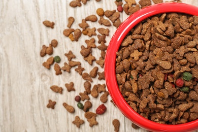 Bowl with food for cat or dog on wooden background. Pet care