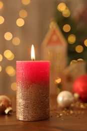 Photo of Beautiful burning candles with Christmas decor on wooden table against blurred festive lights