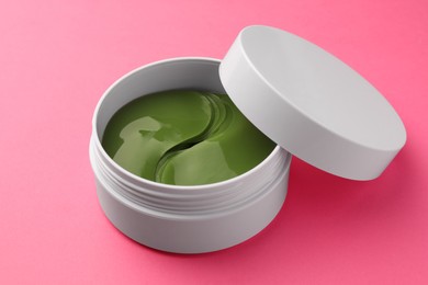 Photo of Jar of under eye patches on pink background, closeup. Cosmetic product