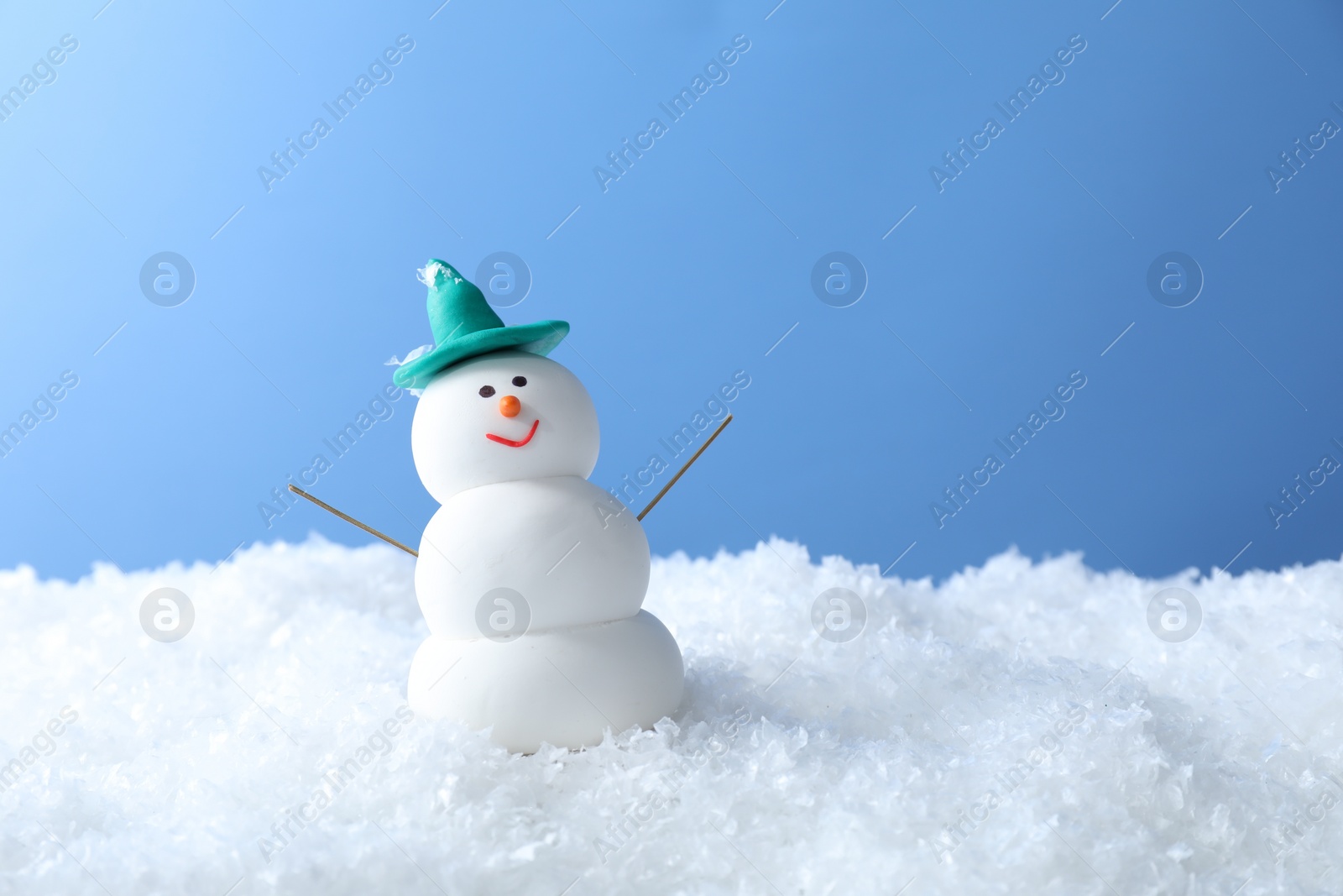 Photo of Funny snowman on snow against light blue background, space for text