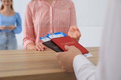 Photo of Agent giving passports with tickets to client at check-in desk in airport, closeup