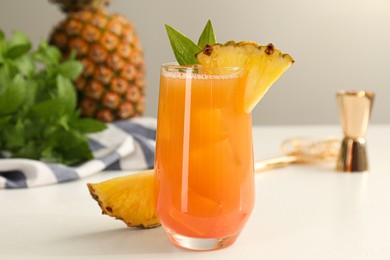 Photo of Tasty pineapple cocktail in glass and fresh fruit on white table