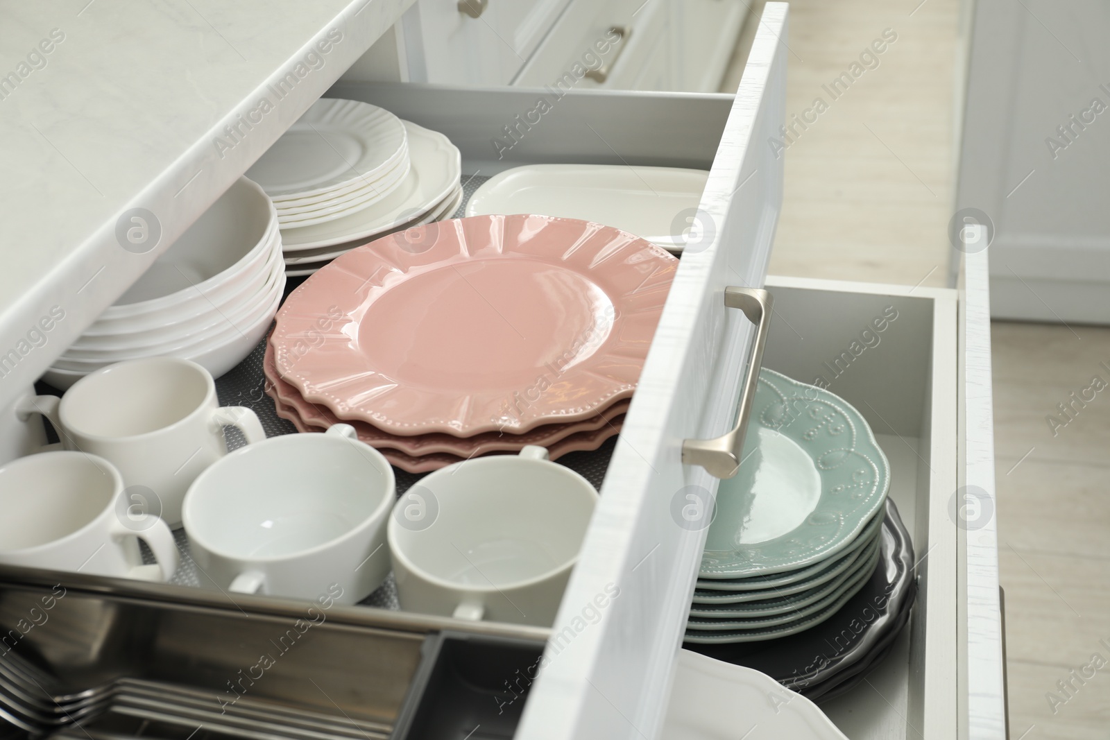 Photo of Clean plates, bowls and cups in drawers indoors