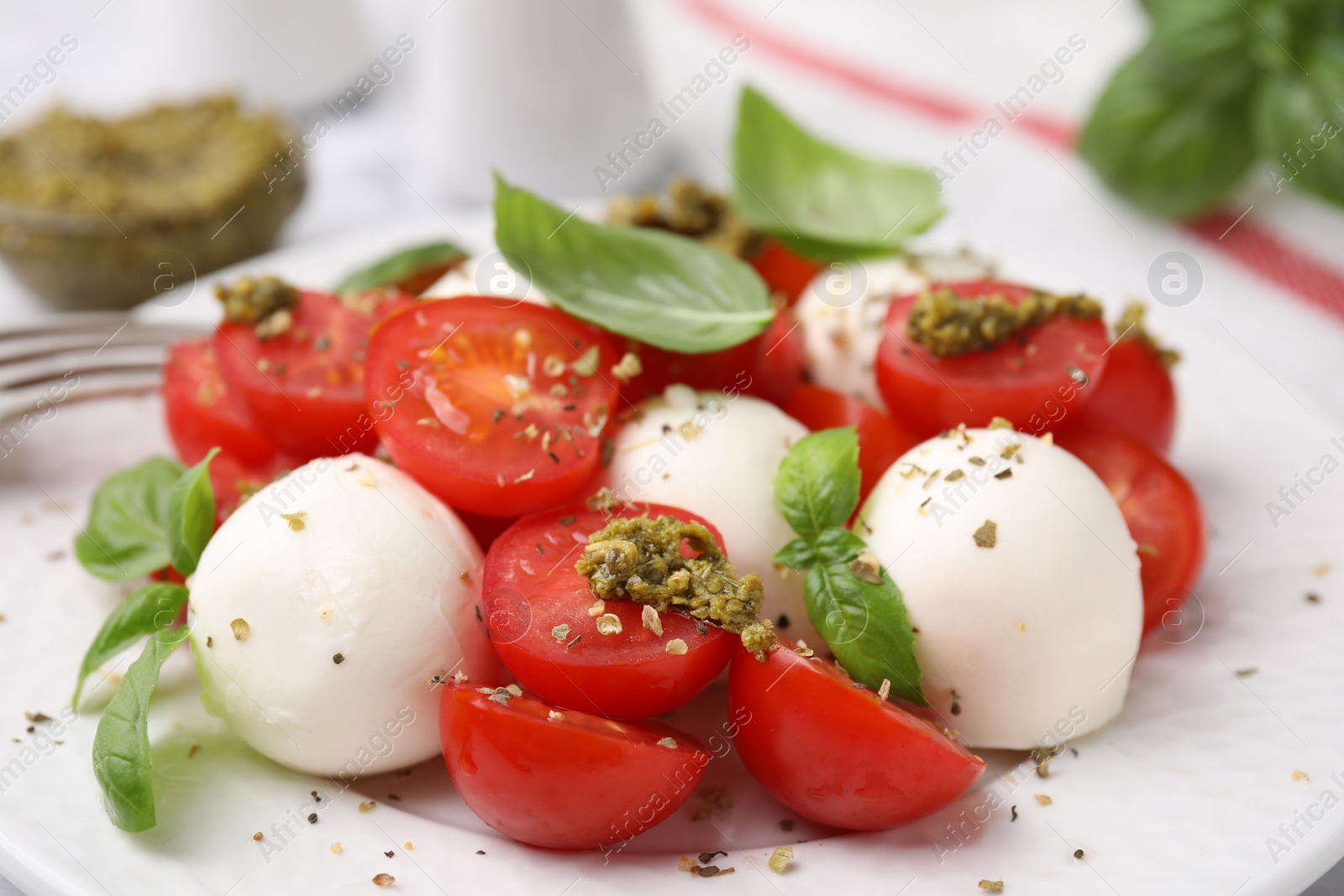 Photo of Tasty salad Caprese with tomatoes, mozzarella balls and basil on plate, closeup